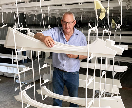 Photo of Kevin Tuck, Managing Director of Tuck's Wood Roof Lanterns, making an inspection in the factory's paintshop in Norfolk, UK